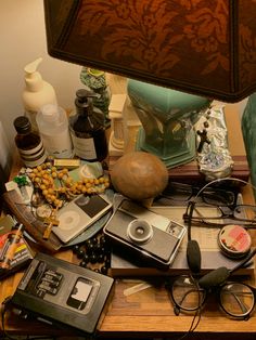 an assortment of personal items on a table with a lamp in the corner behind it