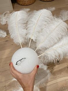 a person holding a white ball with feathers on it in front of a basket and floor