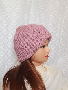 a woman wearing a pink knitted hat on top of a mannequin head