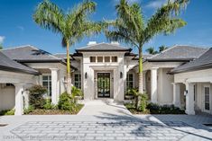 a house with palm trees in front of it and landscaping around the entrance to the home