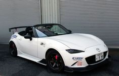 a white sports car parked in front of a garage