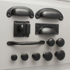 an assortment of black door handles and knobs on a white surface with metal pulls