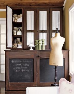 a mannequin is standing in front of an old fashioned cabinet with glass doors