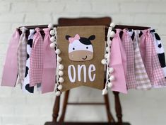 a cow themed banner hanging from a wooden chair