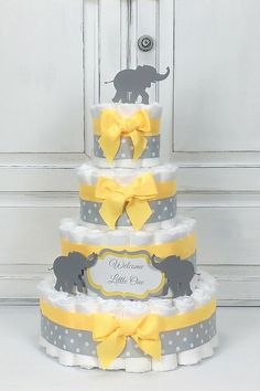 a diaper cake with an elephant on the top and yellow ribbon around the bottom