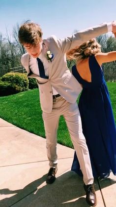 a man and woman dancing on the sidewalk in formal wear with their arms stretched out