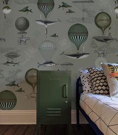 a green locker sitting on top of a bed next to a wall covered in hot air balloons