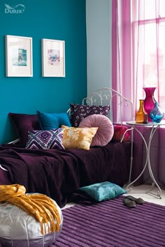 a living room with blue walls and purple curtains on the window sill, colorful furniture