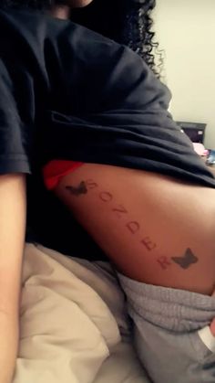 a woman laying in bed with her back turned to the camera and writing on her stomach