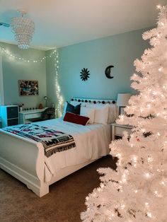 a bedroom decorated for christmas with a white tree in the corner and lights on the ceiling