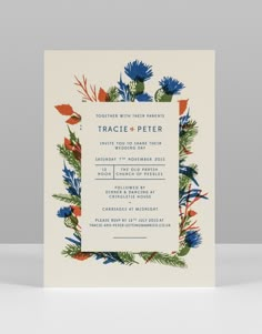 a wedding card with an orange and blue flower border on the front, in white paper