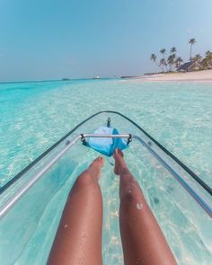 a person laying down in the water on a boat with their feet propped up and facing the camera