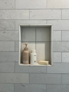 a bathroom with a white tiled wall and some items on the shelf next to it