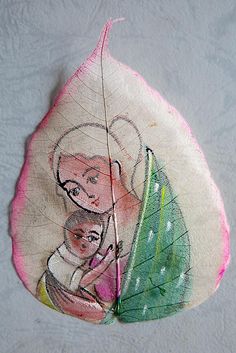 a leaf with an image of a woman holding a baby on it's back