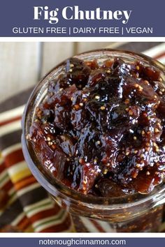 a jar filled with jam sitting on top of a striped table cloth next to a spoon