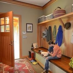 two people sitting on a bench in a room with wooden shelves and hanging items above them