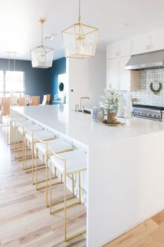 a kitchen with white counter tops and wooden flooring next to a dining room table