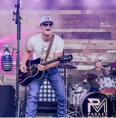 a man standing on top of a stage holding a guitar