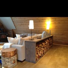 a living room filled with furniture next to a firewood log wall and a fireplace