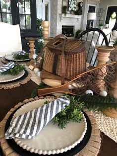 the table is set with black and white plates, wicker baskets and greenery