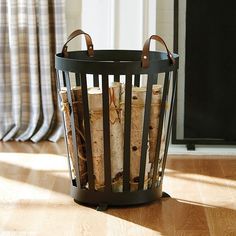 a basket filled with firewood sitting on top of a wooden floor next to a window