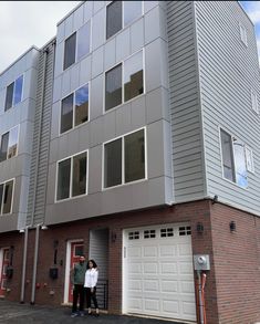 two people standing in front of an apartment building with garages and attached parking spaces