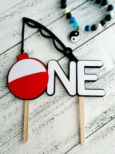 a wooden sign that says one with a red ball hanging from it's side