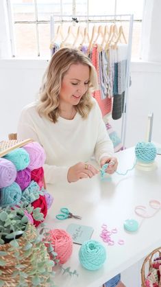 a woman sitting at a table with yarn and crochet