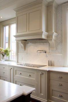 an image of a kitchen setting with white cabinets and gray countertops, including the center island