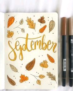 an open notebook with autumn leaves and the word november written in gold ink on it