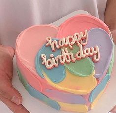 a heart shaped cake with the words happy birthday on it being held by someone's hands