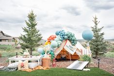 a tent set up with balloons and other items on the ground in front of it