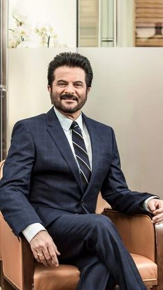 a man sitting in a chair wearing a suit and tie