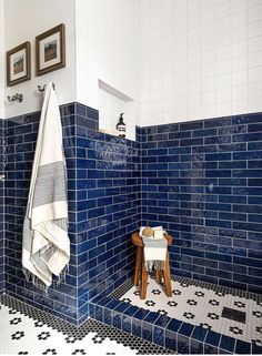 a blue tiled bathroom with two pictures on the wall