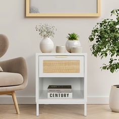 a white table with books and plants on it in front of a framed picture, next to a chair