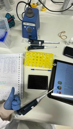 a person in white lab coat and gloves working on an electronic device at a desk