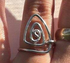 a woman's hand with a ring on it and an open spiral design in the middle