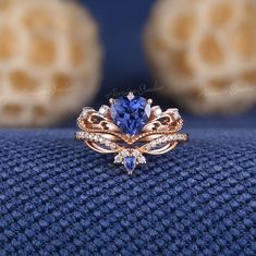 a tan gold ring with blue and white stones on it, sitting on top of a blue cloth