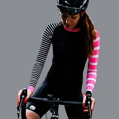 a woman riding a bike with pink and white stripes on her arm sleeved shirt