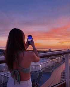 a woman standing on top of a balcony holding a cell phone up to her face