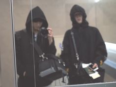 two people in black hoodies are taking pictures