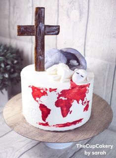 a cake decorated with red and white icing has a wooden cross on the top