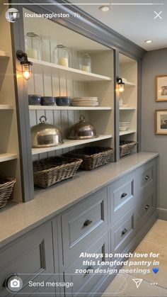 a kitchen with gray cabinets and baskets on the counter top, along with pictures above it