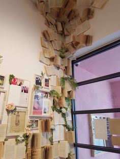 a room that has many books on the wall and plants growing out of the book pages