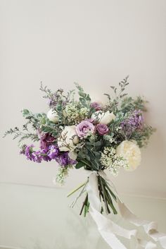 a bouquet of flowers sitting on top of a table next to a white ribbon tied around it