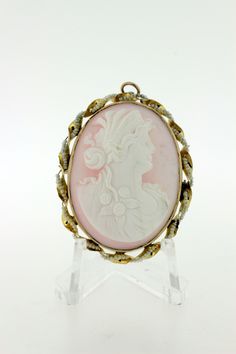 What a unique 10 karat yellow gold carved cameo brooch!! This alluring piece portrays a female figure with roses braided in her hair. The cameo is shell and the body f the brooch is bordered with a swirled ribbon of 10K yellow gold with seed pearls strung along. The brooch is a convertible piece that could also be worn on a chain. If you require a chain, please feel free to convo and we can get you a quote for that. This wonderful piece measures 40.4 millimeters long 31.9 mm wide and it's 15.2 m Female Figure, Cameo Brooch, Stick Pins, Seed Pearl, Her Hair, Brooches, Swirl, Convertible, Seeds