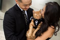 a man in a suit and tie holding a cat with his face close to the woman's chest