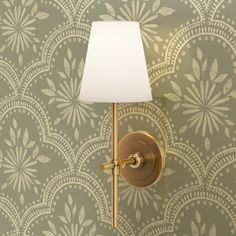 a wall lamp with a white shade on it next to a green wallpapered wall