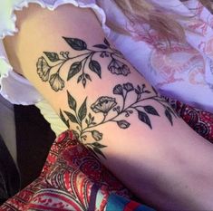 a woman's arm with flowers and leaves on it