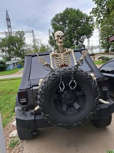 a skeleton sitting on the back of a jeep with chains hanging from it's tires